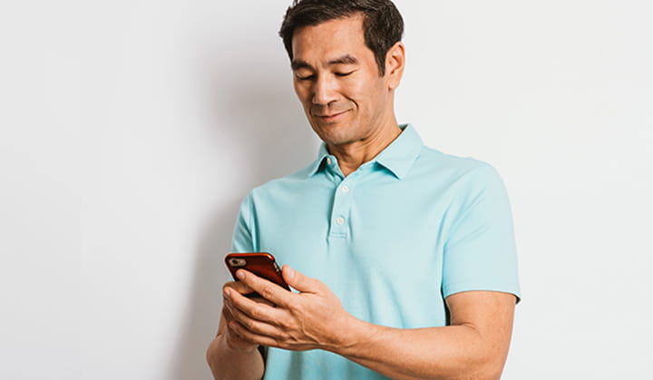 Person in polo shirt on mobile phone sending money with Zelle® and BOK. 